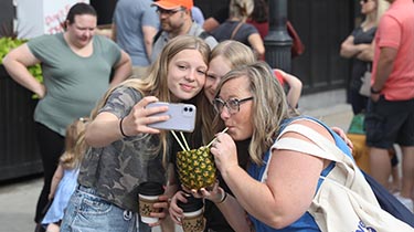 a group of people taking a photo of themselves drinking from a pineapple