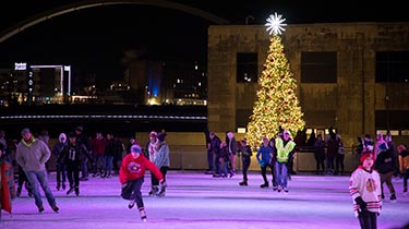 ice skating outdoors with a Christmas tree in the background