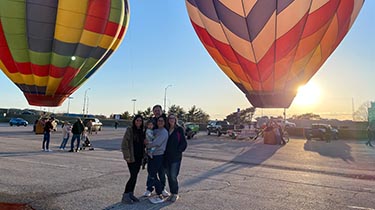 a group of people with two hot air balloons in the background