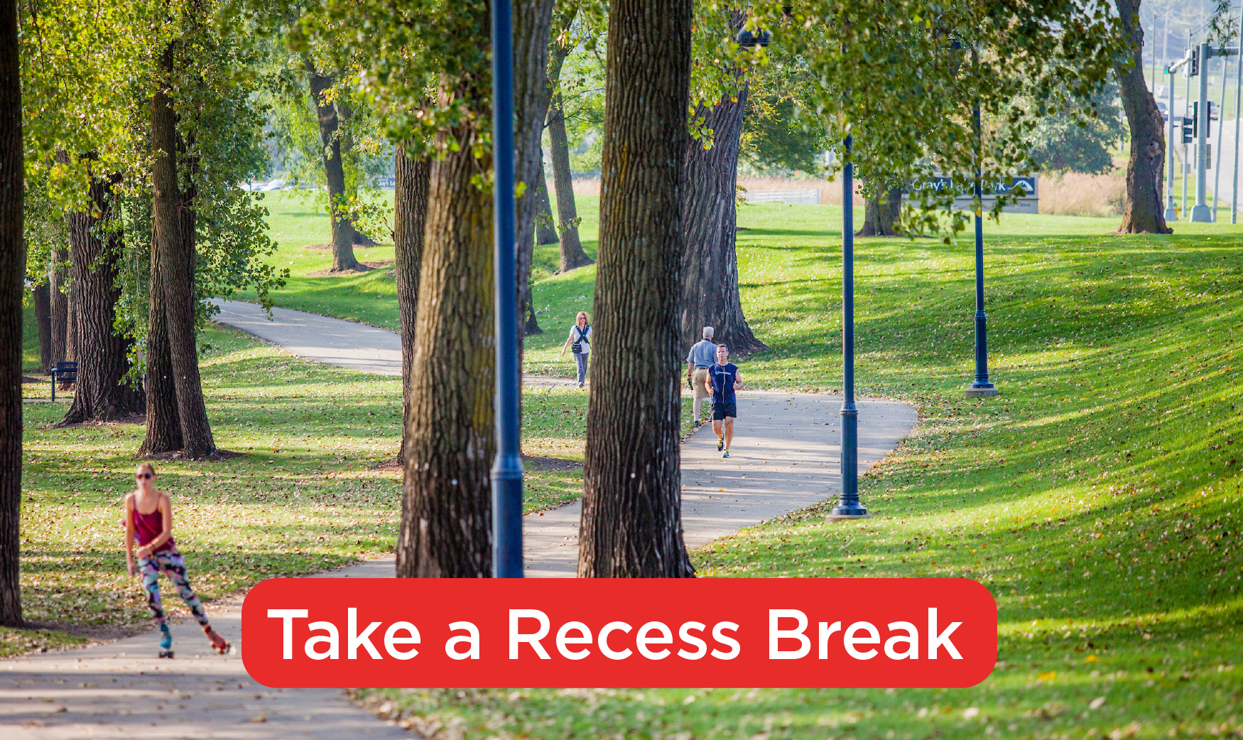 A far off view of a trail with a woman rollerblading and a man running. Text at the bottom of the photo reads: Take a Recess Break