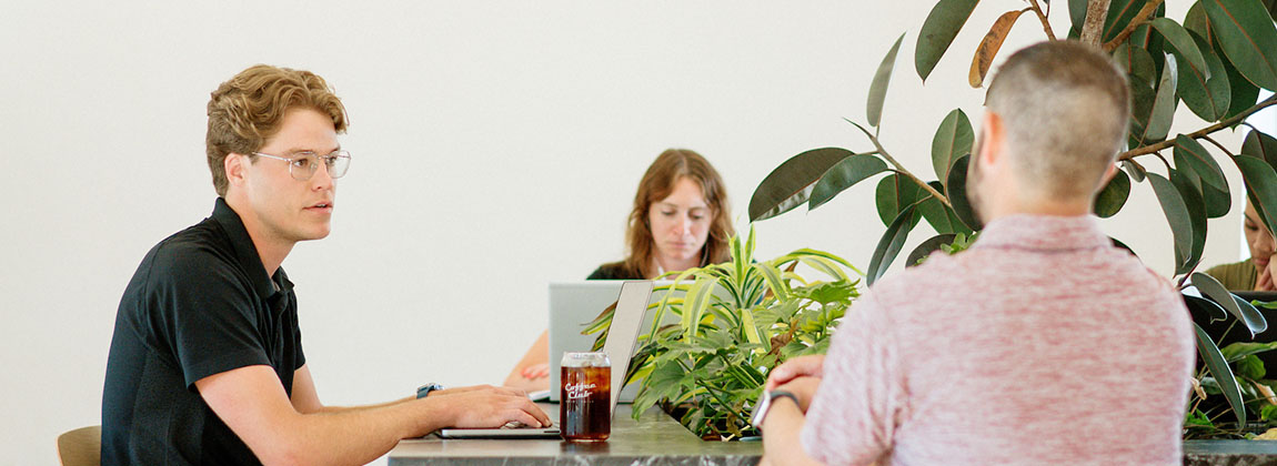 Three people working a table in a coffee shop