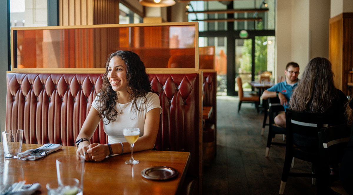 an individual sitting at a booth smiling