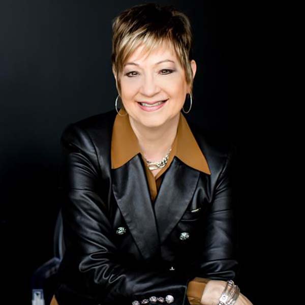 A woman with short hair sitting and smiling for her photo.