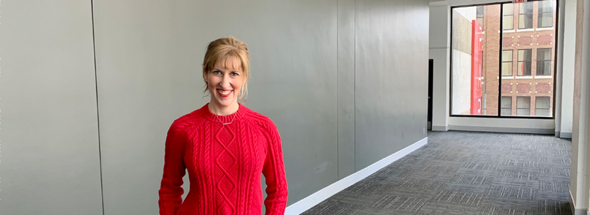 A woman smiling in front of a blank wall in the skywalk