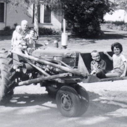 people on tractor grandfather and grandchildren