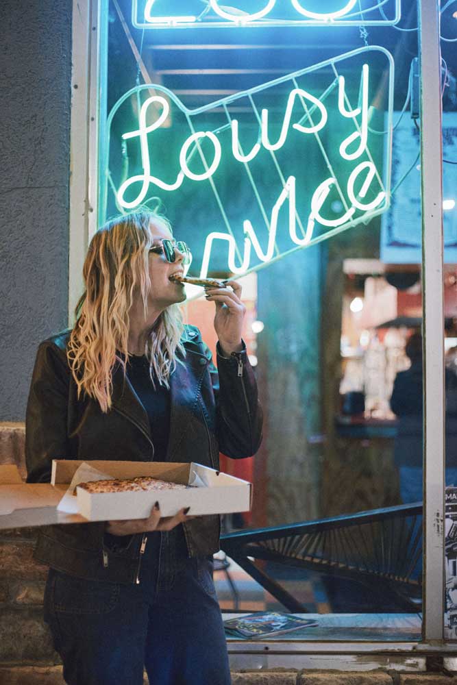 The Avenues a woman eating a slice of pizza