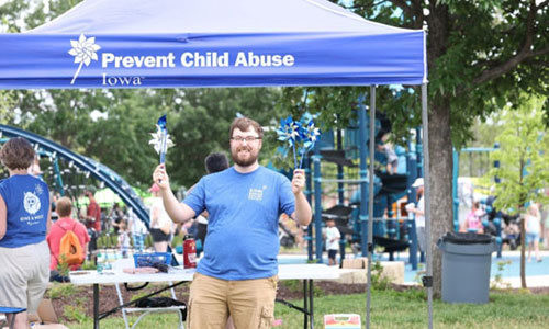 Prevent Child Abuse Iowa event man with pinwheels by tent