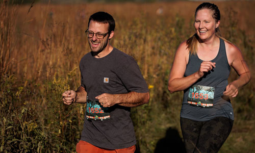 two people running outside through tall grasses