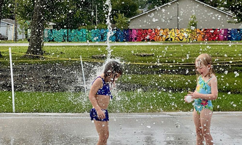 kids at splash pad in front of mural