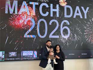 A family smiling for a photo in front of a Match Day 2026 sign. 