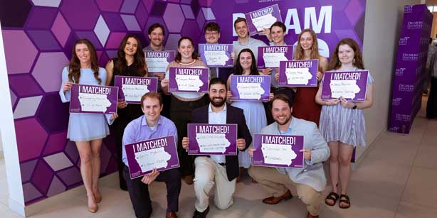 A group of students smiling with their match day signs