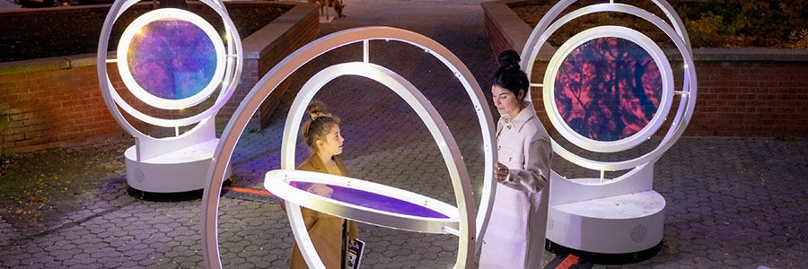 Two people interacting with the gyroscope-like forum at night time.