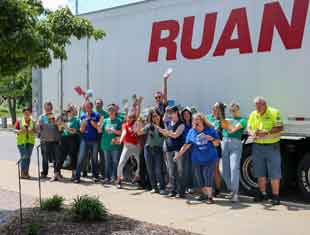a group of volunteers posing with books in front of a semi truck