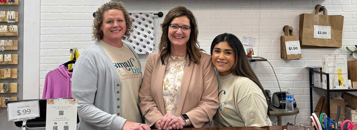 three people posing behind the counter