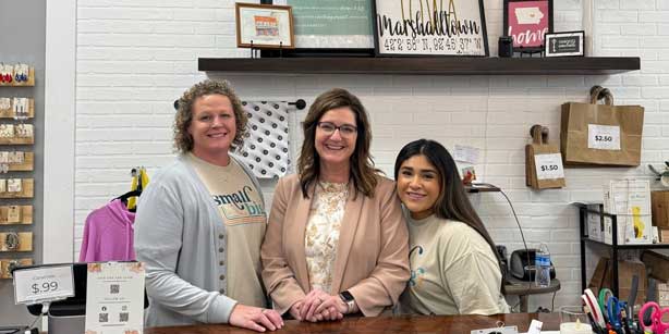three people posing behind the counter