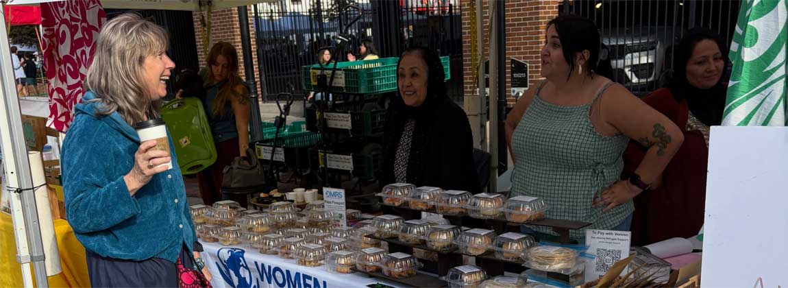 woman with coffee at a farmers' market booth