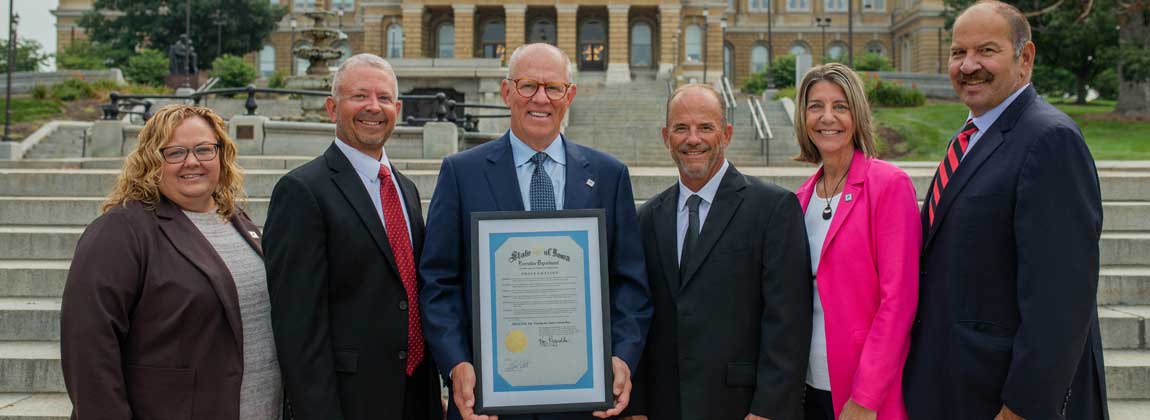 six people posing in front of the Iowa State Capitol