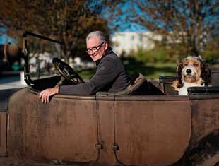 man and dog in a classic car
