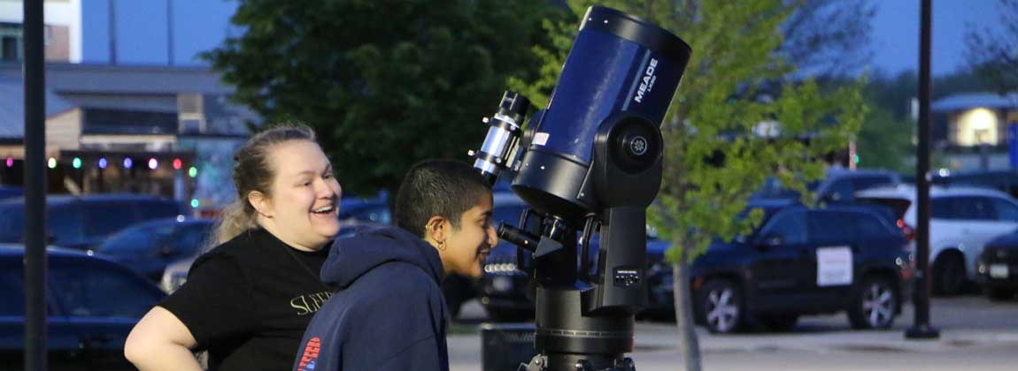 two people viewing the sky through a telescope