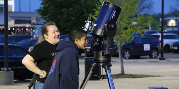 two people viewing the sky through a telescope