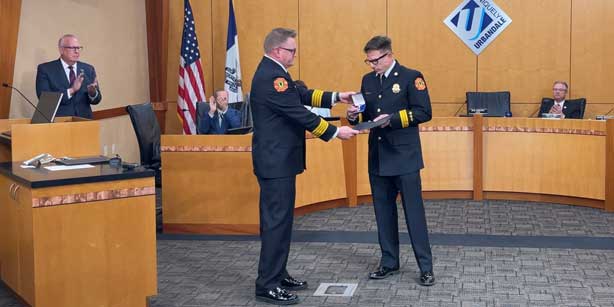 two men shake hands at city council meeting