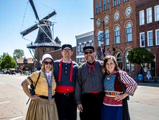 four people posing in front of a windmill