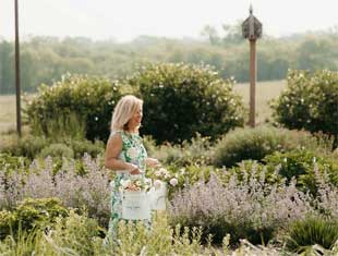woman walking with buckets of flowers
