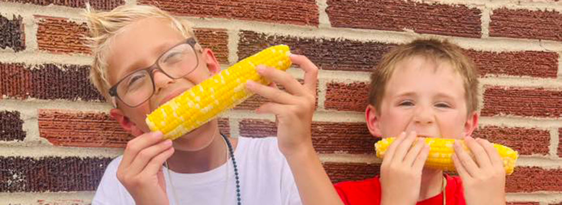 two boys eating sweet corn