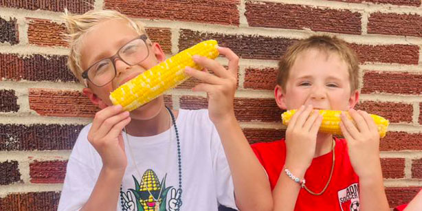 two boys eating sweet corn
