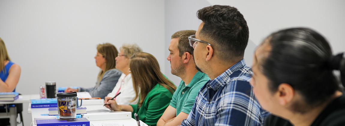 People sitting at a table listening to someone speak
