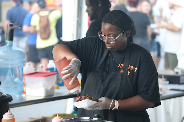 A vendor pouring sauce onto a food item